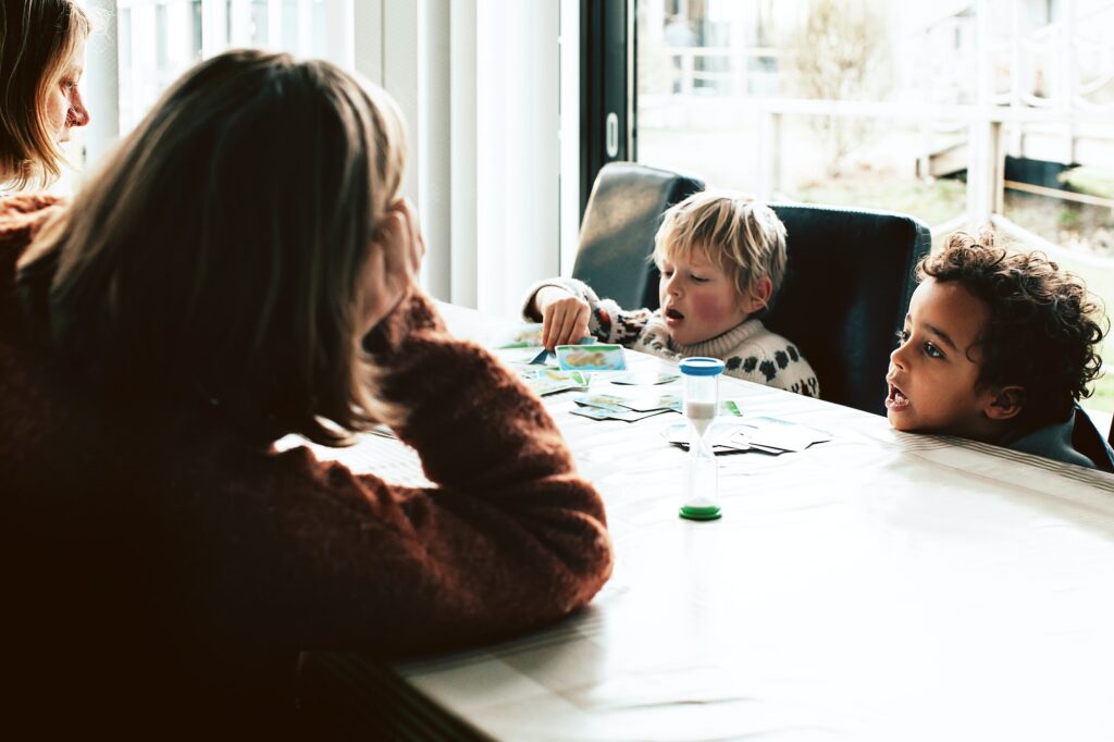 Two mothers play cards with their children